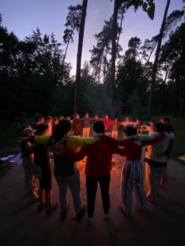 Учасники таборових занять палять багаття, обійнявшись у колі навколо вогню