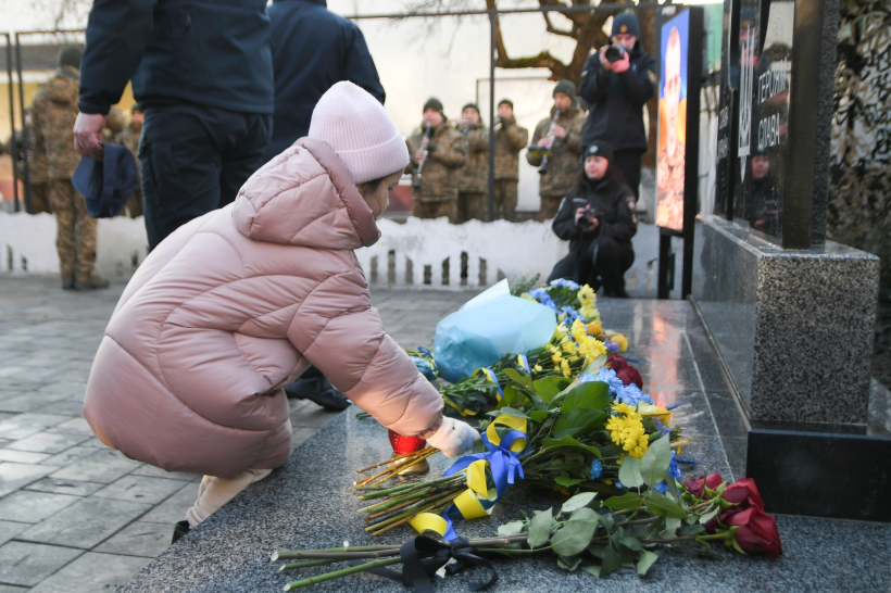 дівчинка кладе квіти до меморіалу