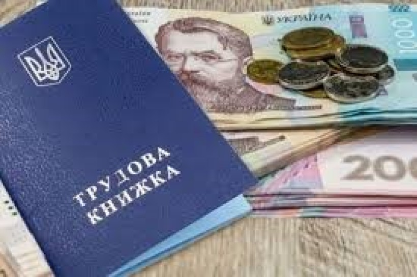 Біля трудової книжки лежать купюри та монети. Фото ілюстративне