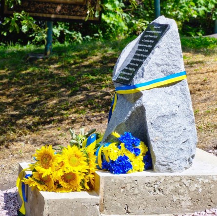 Пам'ятний знак Олені Телізі та жовто-блакитні квіти які лежать біля підніжжя