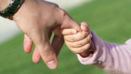 Фото ілюстративне - маленька дитяча рука тримає дорослу руку за палець