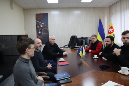 В кабінеті за круглим столом сидять учасники зустрічі та спілкуються