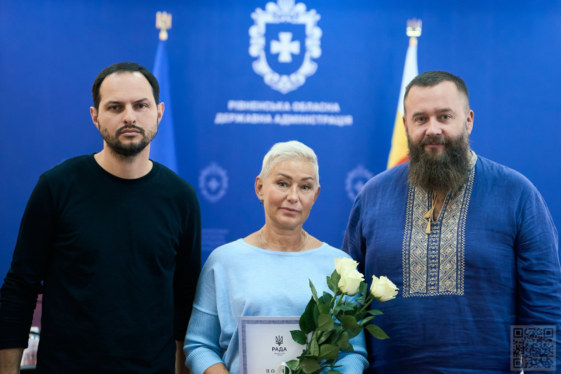 Олександр Коваль та Олексій Бучинський вручили тренерці грамоту та квіти і позують для памятного фото