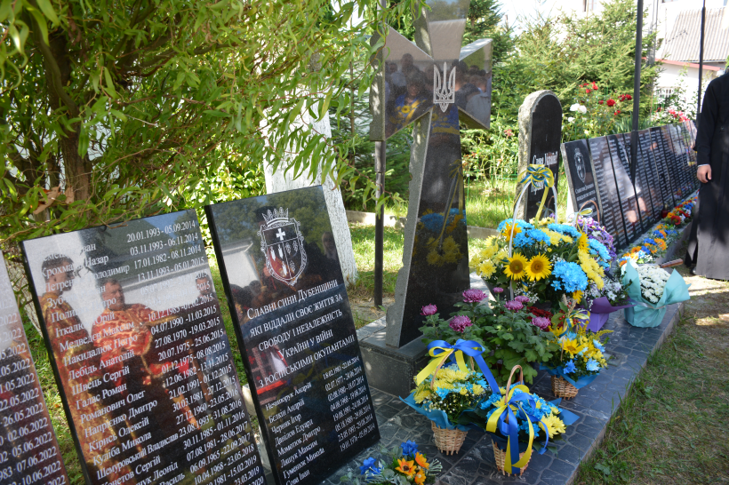 Пам'ятні плити на яких викарбувано імена полеглих воїнів біля яких стоять корзини з квітами