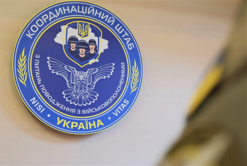 Фото ілюстративне - на стіні висить  герб, де на синьому тлі розміщено символ головного управління розвідки сову та написано Координаційний штаб з поводження із військовополоненими