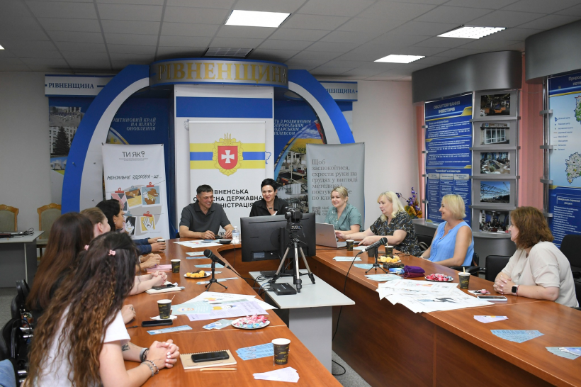 Перший заступник голови Рівненської ОДА Сергій Подолін та заступниця голови Рівненської ОДА Людмила Шатковська під час зустрічі із консультантами програми "Ти як". Вони сидять за столом, спілкуються, перед ними кава та цукерки. Очевидно розмова проходить у невимушеній атмосфері, всі посміхаються