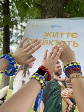 Дитячі руки з браслетами на фоні плакату "Життєстійкість"