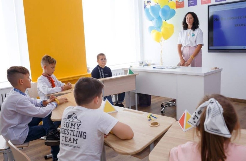 У Світлому класі за чительським столом стоїть вчителька. Вона привітна та усміхнена.  За партами, які стоять утворюючи коло, сидять діти. Вони слухають вчителя