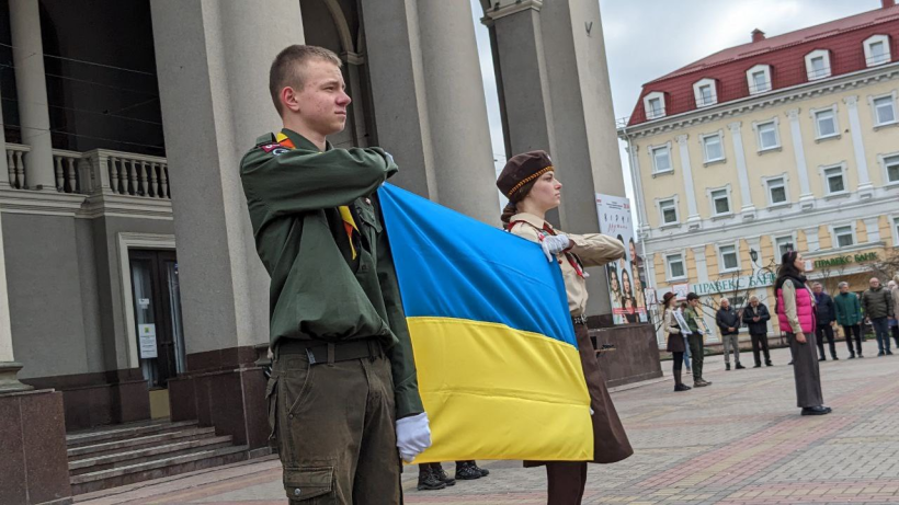 Двоє пластунів тримають прапор України на площі перед театром, де аідбуваєтьмя присяга Національної скаутської організації «Пласт»