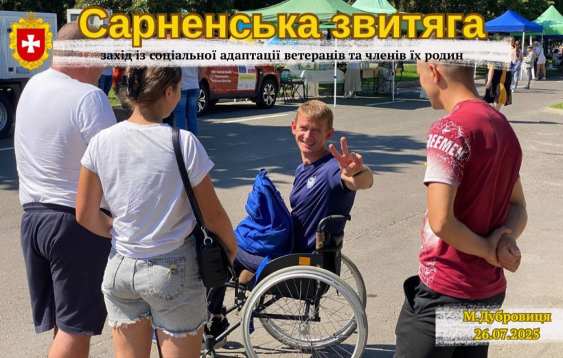 На площі міста у кріслі колісному сидить ветеран, біля нього стоять молоді люди. Він посміхається і рукою показує знак перемоги "V". Зверху напис - Сарненська звитяга.