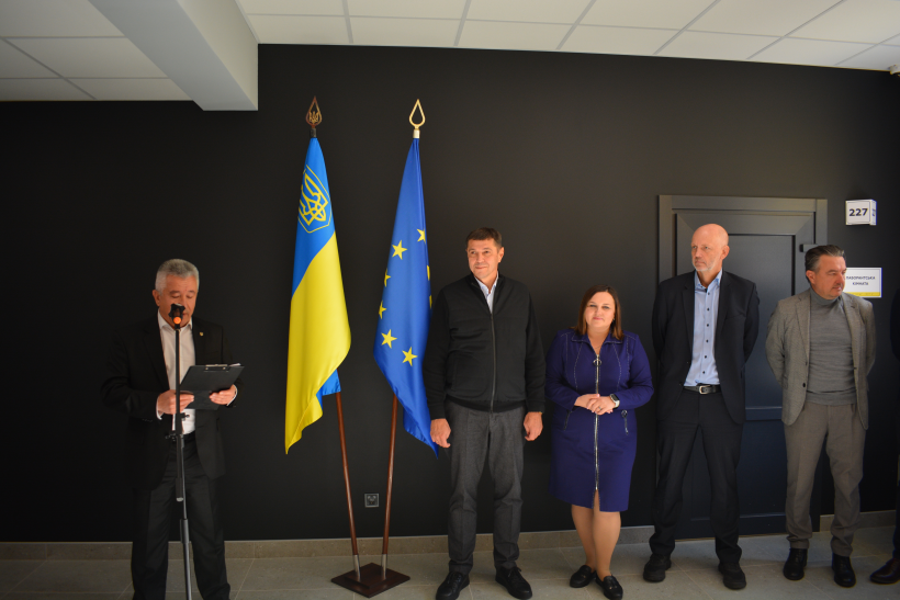 У фойє училища стоять почесні гості та перший заступник голови Рівненської ОДА Сергій Подолін. Біля мікрофону стоїть директор Департаменту освіти і науки ОДА Петро Коржеввський із папкою і звертається до присутніх