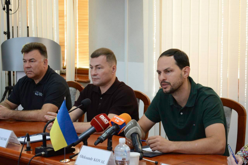 Начальник Рівненської ОВА Олександр Коваль та головва обласної ради сидять за столом та спілкуються з лікарямі з Італії. Перед ними стоять мікрофони регіональних телеканалів