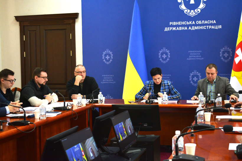 Учасники зустрічі сидять за столом та обговорюють робочі питання