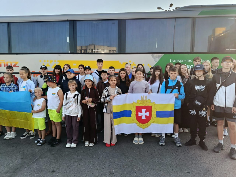 Група дітей стали для загального фото. Вони посміхаються і тримають у руках прапор Рівненщини