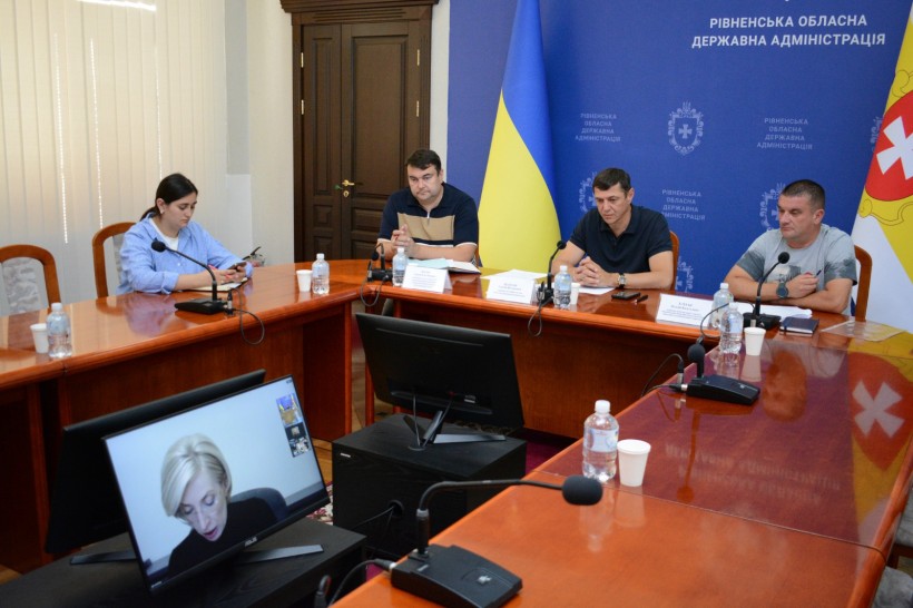 За столом під час наради сидить перший заступник голови Рівненської ОДА Сергій Подолін та інші учасники, на моніторі - Заступниця Керівника Офісу Президента України Ірини Верещук веде нараду