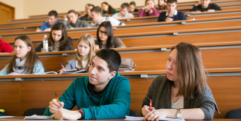 В аудиторії за партами сидять студенти: хлопці та дівчата щось записують та слухають викладача