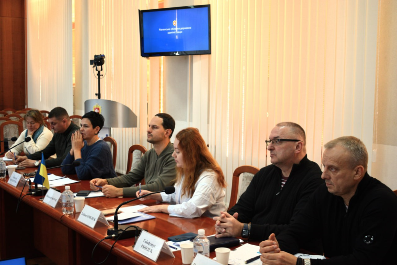У залі Рівненської ОДА проходить зустріч начальника ОВА Олександра Коваля, заступниці голови ОДА Людмили Шатковської, керівників структурних підрозділів ОДА із представниками норвезької фірми. Вони сидять за столом та спілкуються.