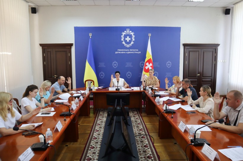Засідання робочої групи - всі сидять за столом та голосують піднявши руку.