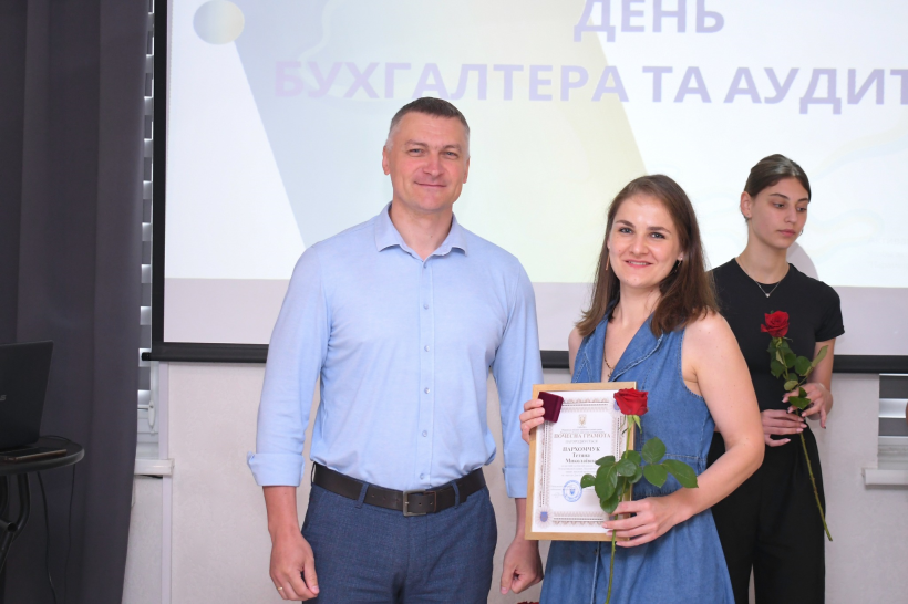 Заступник голови Рівненської ОДА Олександр Кохан  вручає грамоту та відзнаку одній з кращих бухгалтерів області. Обоє посміхаються