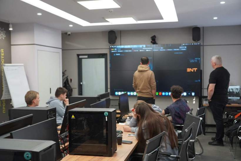 У комп’ютерному класі проходить практичне заняття. Учасники працюють за стаціонарними комп’ютерами, а двоє чоловіків - начальник Рівненської ОВА Олександр Коваль та його заступник Олександр Терещенко біля великого екрана демонструють матеріали. На екрані відкрито цифрову платформу чи програмне середовище.