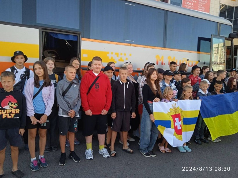 Діти Рівненщини, які поїхали на одоровлення, біля автобуса тримають в руках Прапор Рівненської області та Державний Прапор України