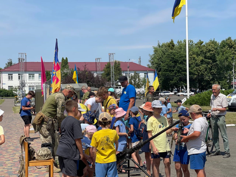 На площі стоїть багато дітей та дорослих, які розглядають різну зброю. Її представляють військові 65-ї бригади