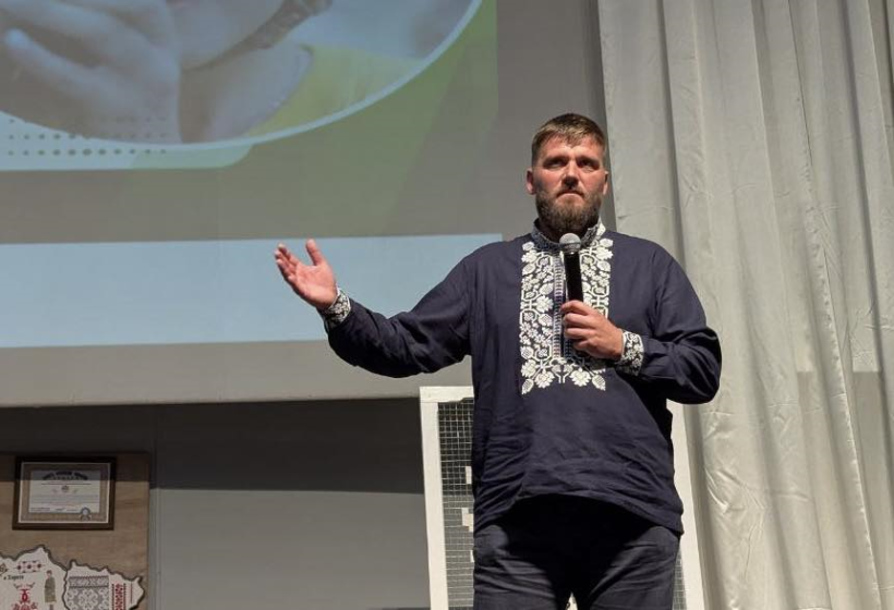 Віктор Мельничук стоїть на сцені із мікрофоном у руках і у вишиванці
