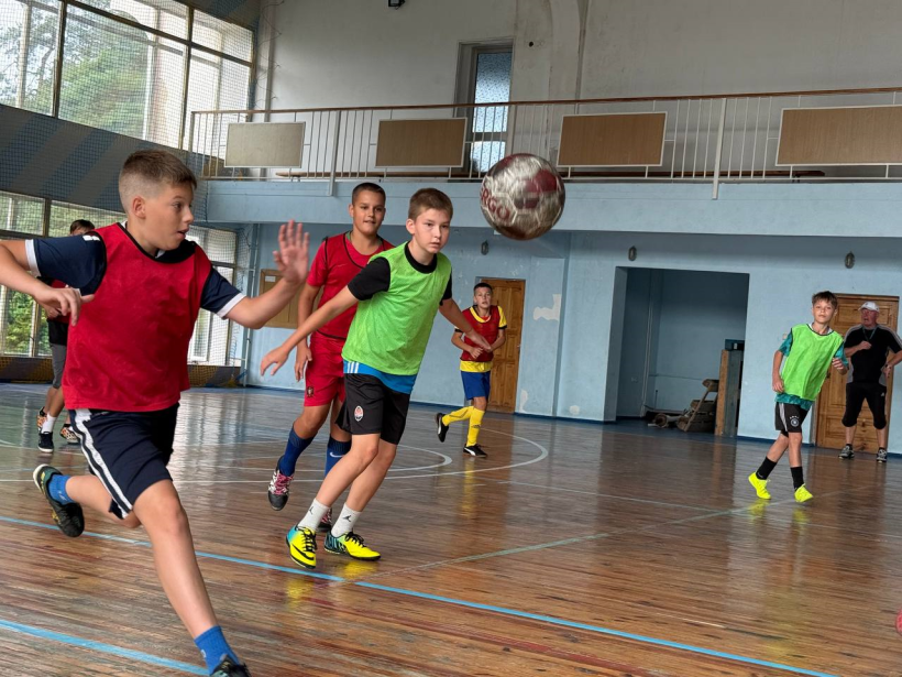 Хлопці у спортивних формах грають фублол у спортзалі