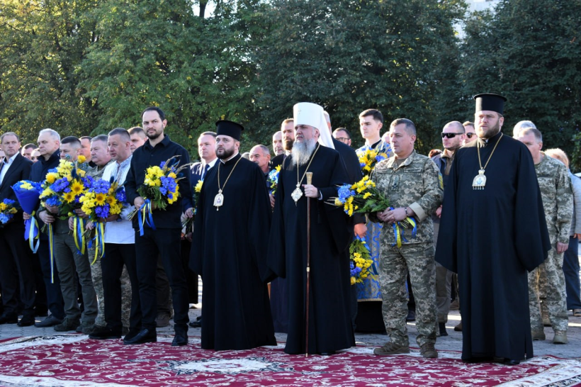 На площі біля Покровського собору стоять представники духовенства, керівництво області та військові із квітами в руках