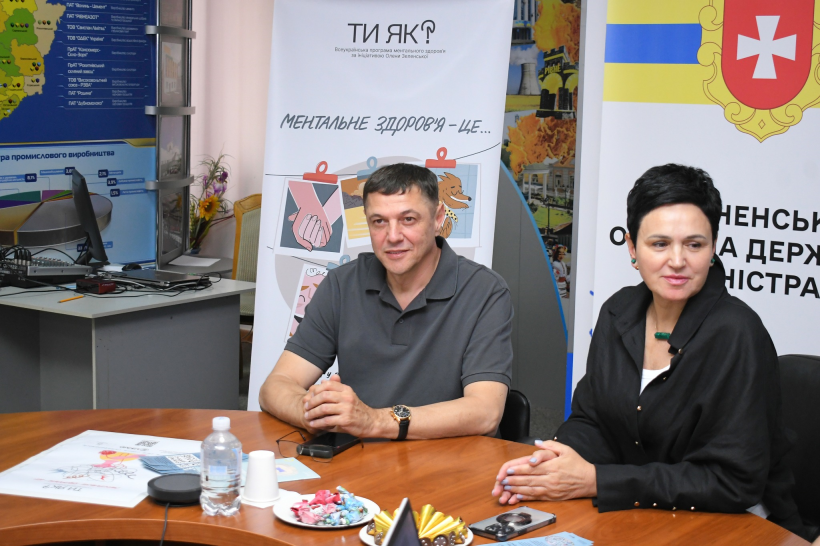 Перший заступник голови Рівненської ОДА Сергій Подолін та заступниця голови Рівненської ОДА Людмила Шатковська під час зустрічі із консультантами програми "Ти як". Вони сидять за столом, спілкуються, перед ними кава та цукерки. Очевидно розмова проходить у невимушеній атмосфері, всі посміхаються