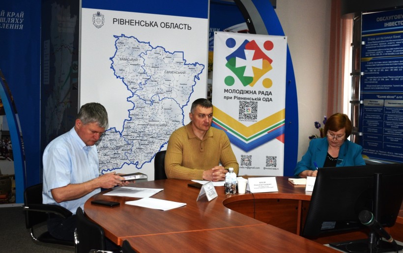 Робоча нарада за участю заступника голови Рівненської ОДА Олександра Кохана, представників структурних підрозділів облдержадміністрації. Засідання відбувається у приміщенні облдержадміністрації на тлі карти Рівненщини та символіки Молодіжної ради.