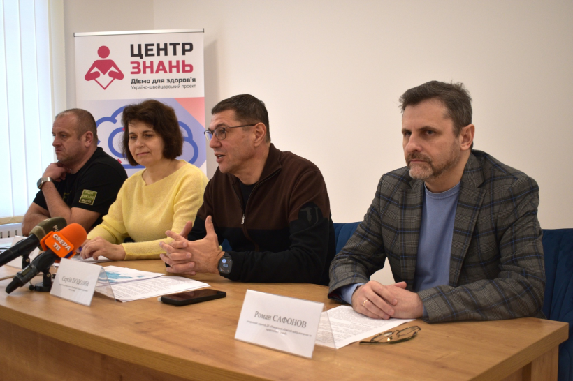 За столом сидять троє чоловіків та жінка. На столі перед ними лежать документи, стоять таблички. На фото - брифінг за участі першого заступника голови Рівненської ОДА Сергія Подоліна, генерального директора Рівненського обласного ЦКПХ Романа Сафонова, медичної директорки Рівненської обласної інфекційної лікарні Наталії Стецій та голови правління БО «Мережа 100 відсотків життя Рівне» Євгена Баборикіна.