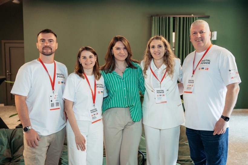 На фото п’ятеро людей, які позують разом у приміщенні. Четверо учасників одягнені у футболки з написом «Digital Power» та мають бейджі учасників заходу.