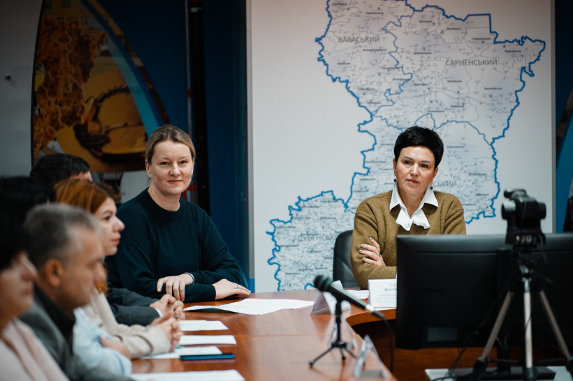 Учасники зустрічі сидять за столом та активно спілкуються