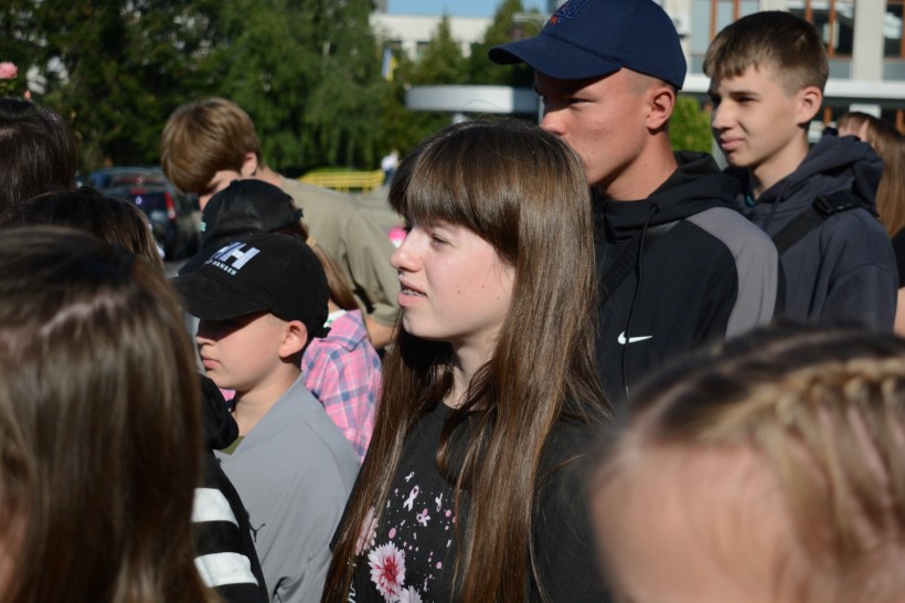 Діти стоять та слухають спікерів, які до них звертаються