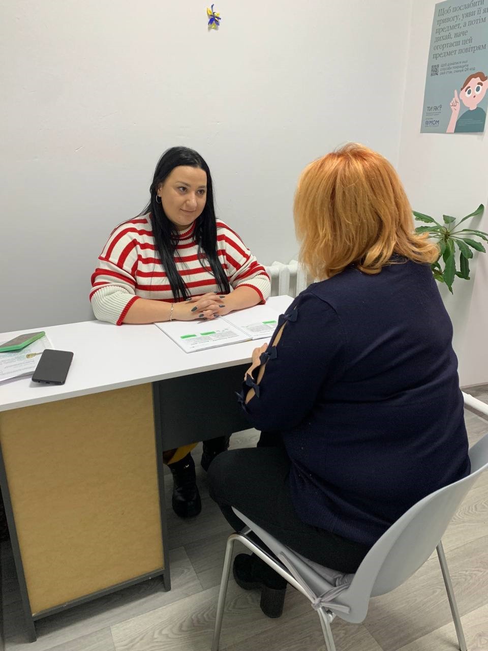 Людина та фахівець з ментального здоровя сидять за столом, проводить консультацію