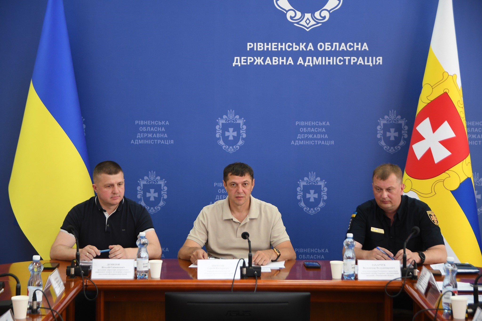 Заступник директора департаменту цивільного захисту на охорони здоровя ОДА В.Демидов, перший заступник голови ОДА С.Подолін, т.в.о. начальника Головного управління ДСНС України у Рівненській області В.Захарчук - за столом під час засідання на фоні синього банера Рівненської обласної державної адміністрації, Державного прапора України та прапора Рівненської області