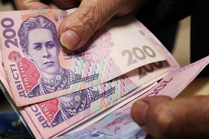 У руках людина тримає купюри номіналом 200 грн. Фото ілюстративне