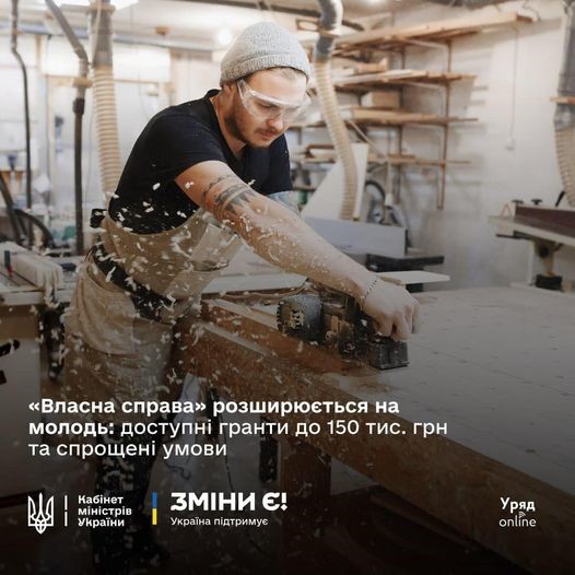Молодий чоловік, який працює на деревообробному верстаті в майстерні. Він одягнений у чорну футболку, світлі штани, бежеву шапку та захисні окуляри. Навколо нього видно дерев'яну стружку та інструменти.

Текст на зображенні інформує про програму "Власна справа", яка розширюється для молоді: доступні гранти до 150 тисяч гривень та спрощені умови. Внизу розміщено логотипи Кабінету Міністрів України та ініціативи "Зміни є!". Фото ілюстративне