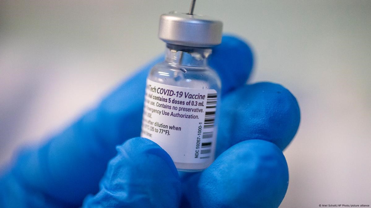 Флакон з вакциною у руці в синій перчатці